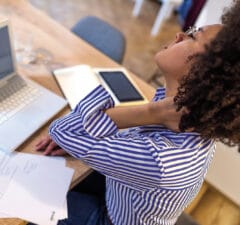 Femme souffrant du syndrome de l’angulaire, assise au bureau devant son ordinateur